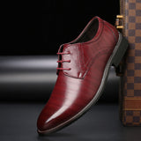 Scarpa elegante da uomo in pelle rossa lucida, con lacci, suola nera e dettagli cuciti, posizionata accanto a una valigia a scacchi.
