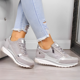 Scarpe da ginnastica grigie da donna, con dettagli in pelle scamosciata e cerniera, indossate con jeans chiari strappati. Moda casual e trendy.