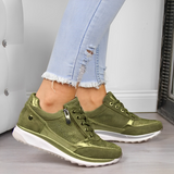 Scarpe da ginnastica verde oliva su gambe con jeans strappati chiari, moda casual donna, calzature trendy, pavimento in legno, arredamento moderno.