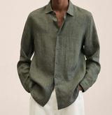 Camicia uomo in lino verde oliva, maniche lunghe, abbinata a pantaloni bianchi. Moda maschile elegante e casual, stile estivo.