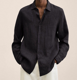 Camicia nera in lino da uomo, maniche lunghe, abbinata a pantaloni chiari. Moda elegante e casual, ideale per look estivi e primaverili.