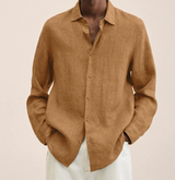 Camicia di lino marrone chiaro da uomo, maniche lunghe, abbinata a pantaloni bianchi. Moda maschile elegante e casual.