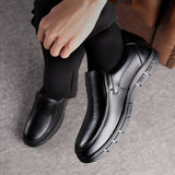 Scarpe eleganti da uomo in pelle nera, design slip-on, suola antiscivolo, indossate con pantaloni scuri. Ideali per look formale e business.