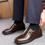 Scarpe eleganti da uomo in pelle marrone, indossate con pantaloni blu scuro. Design slip-on, suola robusta, ideali per look formale e casual.