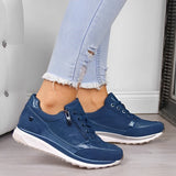 Jeans chiari strappati e sneakers blu da donna su pavimento in legno. Scarpe casual eleganti, moda femminile, calzature comode.