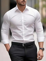 Uomo in camicia bianca elegante e pantaloni neri, cammina in città. Moda maschile, abbigliamento formale, stile urbano.