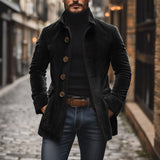 Uomo con cappotto nero elegante, dolcevita e jeans in una strada acciottolata. Moda maschile autunnale, stile urbano sofisticato.