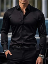 Uomo in camicia nera elegante, orologio al polso, sfondo urbano sfocato. Moda maschile, abbigliamento formale, stile contemporaneo.
