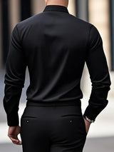 Uomo in camicia nera elegante, visto di spalle, cammina in ambiente urbano. Moda maschile, abbigliamento formale, stile contemporaneo.