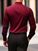 Camicia uomo elegante bordeaux, vista posteriore, abbinata a pantaloni neri. Moda maschile, abbigliamento formale, stile sofisticato.