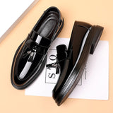 Scarpe mocassino uomo in pelle nera lucida con nappine, suola spessa, design elegante su sfondo beige. Scarpe formali moda maschile.