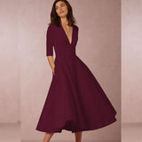 Donna con abito elegante bordeaux a maniche tre quarti e scollo a V, sfondo neutro. Moda femminile, abito da sera, stile sofisticato.