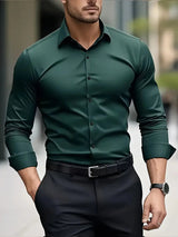 Uomo in camicia verde elegante e pantaloni neri, con orologio al polso, passeggia in città. Moda maschile, abbigliamento formale, stile urbano.