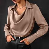 Camicia elegante in raso color beige con colletto e maniche lunghe, indossata con pantaloni neri in pelle. Look sofisticato e moderno.